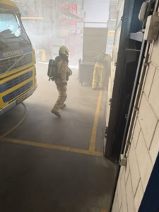 Brandweeroefening met brandweerman in rook en rookmasker.